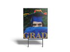 Graduation-themed standee with a person in a blue cap and gown, holding a 'GRAD' sign.