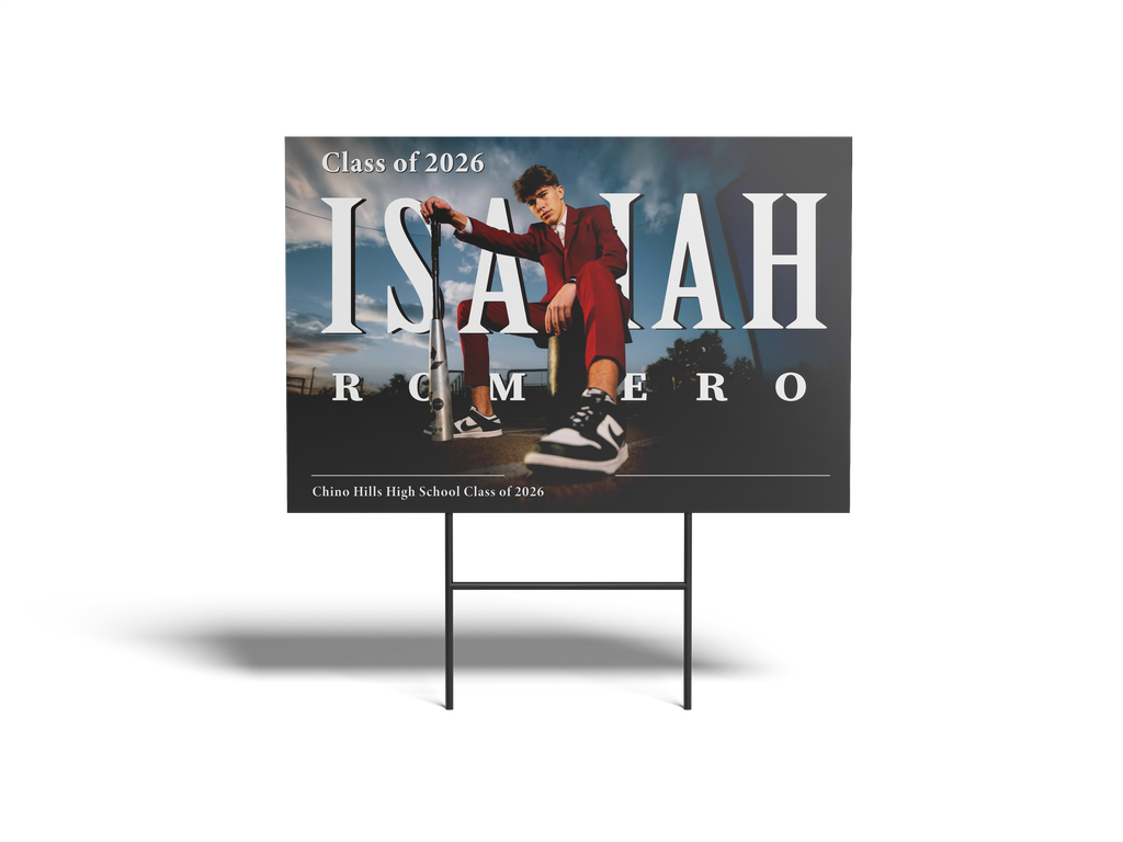 Graduation-themed sign with a person sitting on a bench, text 'Class of 2026', and name 'Isaiah Romero'.