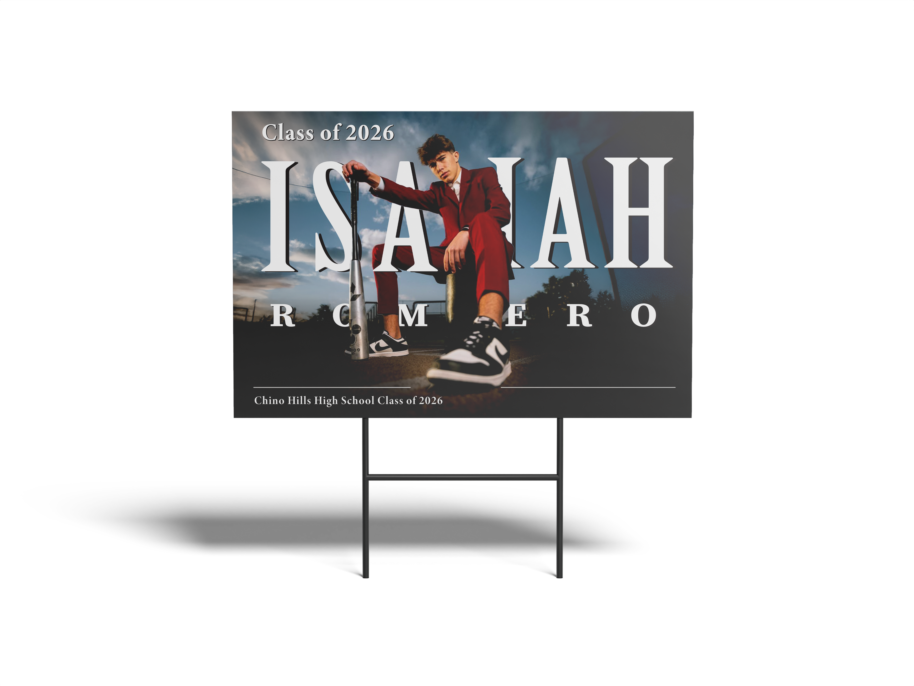 Graduation-themed sign with a person sitting on a bench, text 'Class of 2026', and name 'Isaiah Romero'.